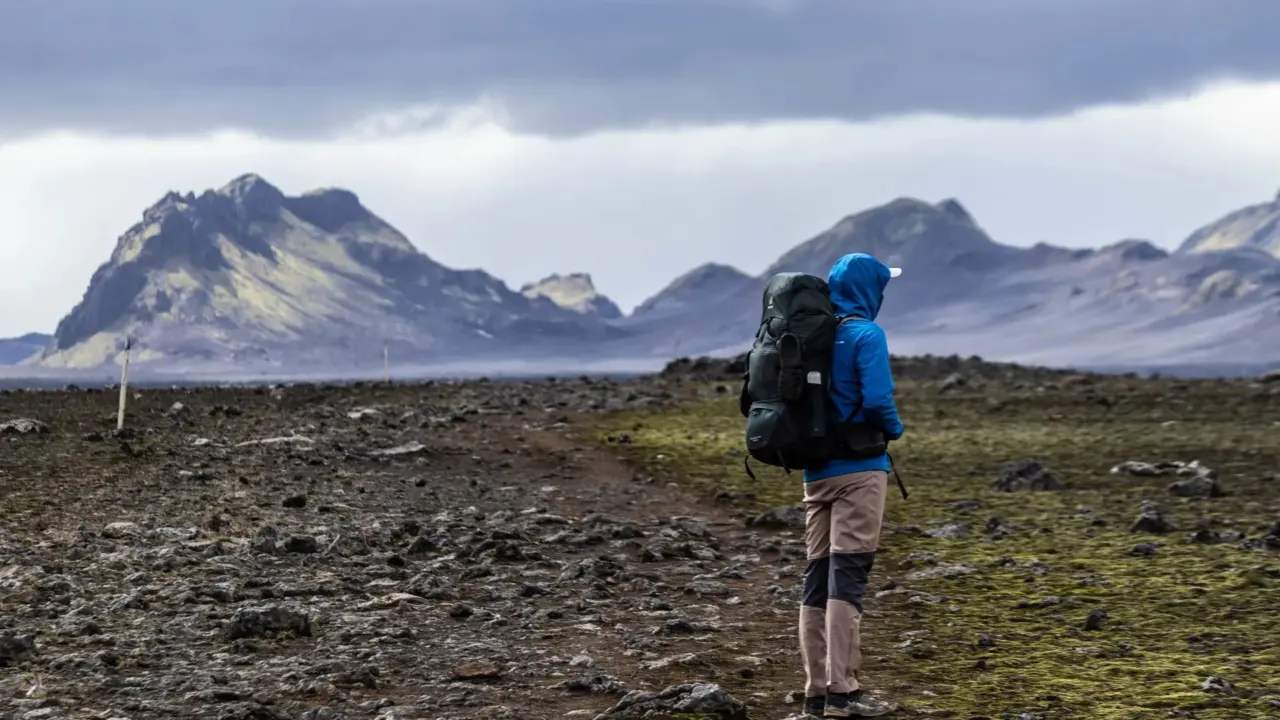 A hiker with a backpack walking along a mountain trail